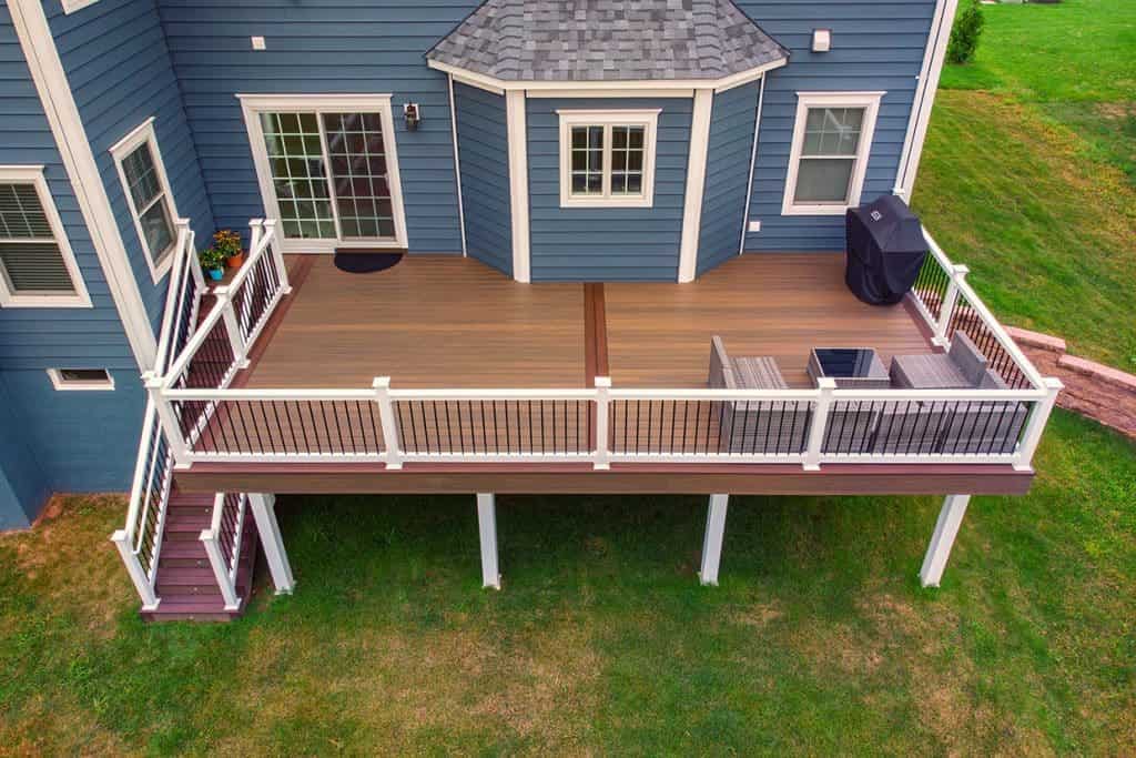 An image of Elegant dark blue house with a cedar balcony and warm wood detailing.
