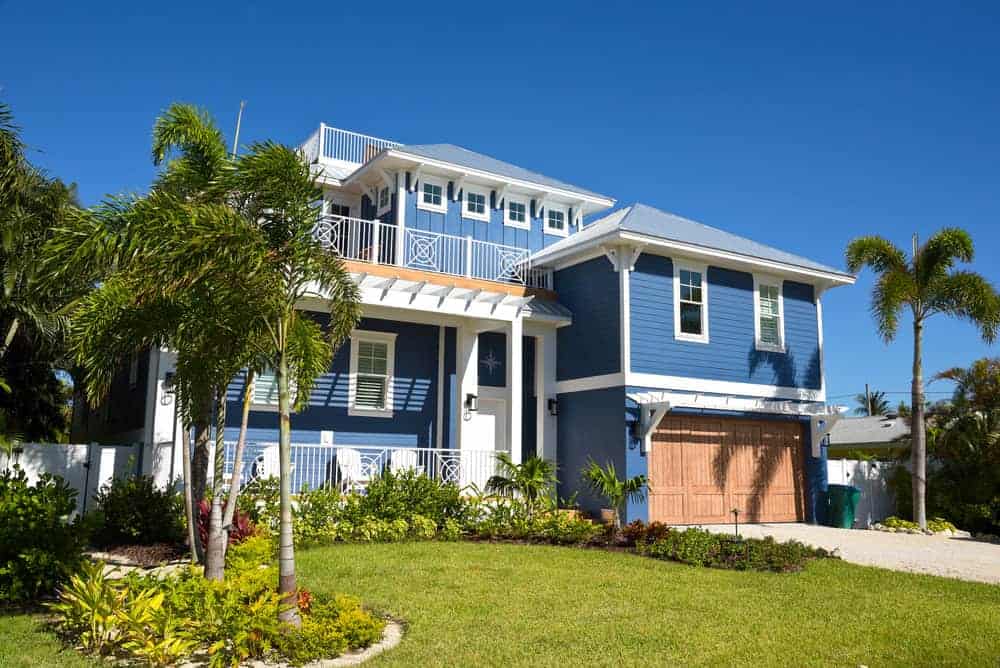 An image of Stylish dark blue house with a custom cedar garage door and modern appeal.
